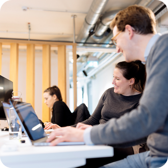 two colleagues friendly laughing talking work laptop square