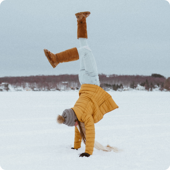 Frau macht einen Handstand im Schnee